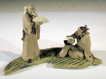 Miniature Ceramic Figurine  Two Mud Men On A Leaf, One Standing holding with Fan, The Other Sitting Reading a Book  - 3" - Culture Kraze Marketplace.com